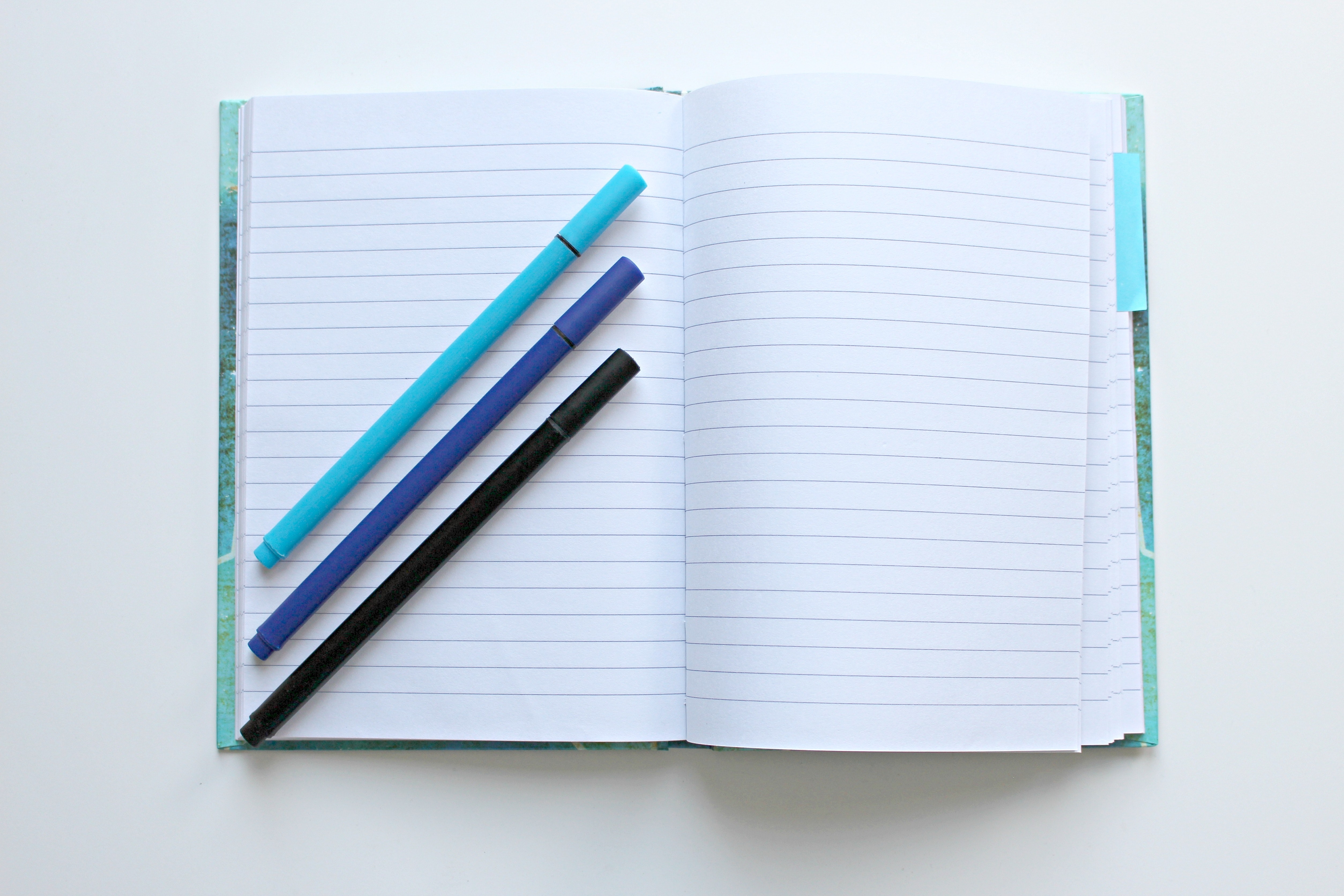 An open notebook and three markers